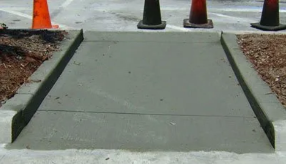 Finishing new concrete curb and sidewalk ramp