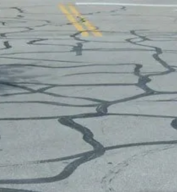 Applying hot rubberized sealant into asphalt cracks