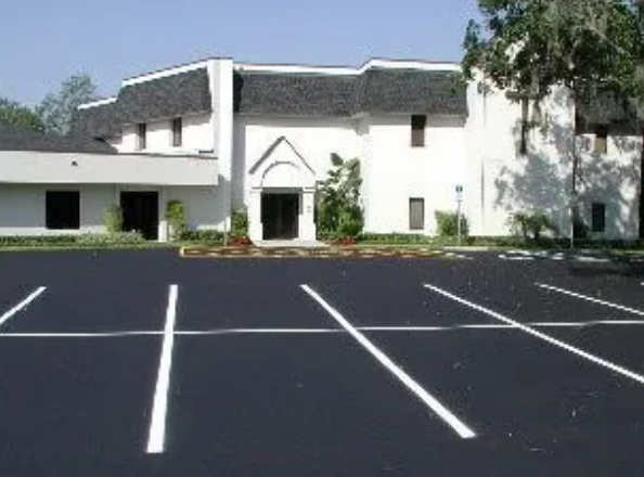 Worker spreading sealer on asphalt with a wide squeegee